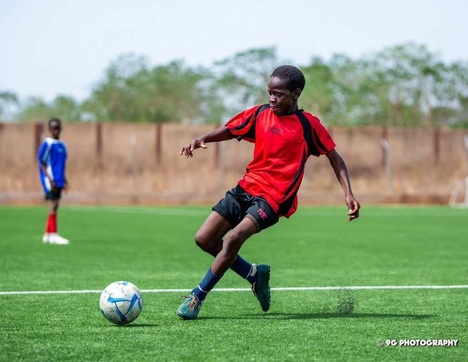Un joueur pousse le ballon en pleine course.